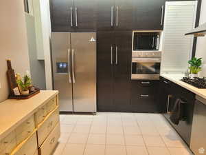 Kitchen with black appliances, exhaust hood, modern cabinets, and light tile patterned floors