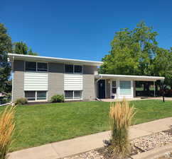 Split level home featuring a front lawn, a carport, covered porch, and brick siding