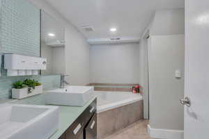 Bathroom featuring double vanity, a garden tub, and recessed lighting