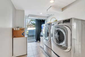 Laundry area with light tile patterned floors, washing machine and dryer, and recessed lighting