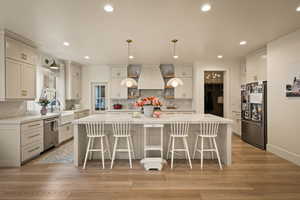 Kitchen featuring stainless steel appliances, a spacious island, a breakfast bar, and light wood-type flooring