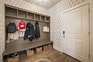 Mudroom featuring light wood finished floors and wallpapered walls