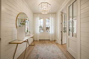 Doorway to outside featuring hanging lights, wooden walls, wood finished floors, and french doors
