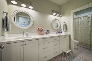 Bathroom with double vanity, shower / tub combo, and wood tiled floors