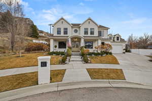 Traditional-style home with a porch, driveway, a garage, and stucco siding