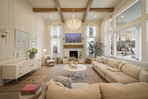 Living area featuring wood finished floors, a fireplace, coffered ceiling, a decorative wall, and suspended lighting