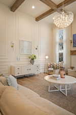 Living area featuring wood finished floors, suspended lighting, beam ceiling, and a decorative wall