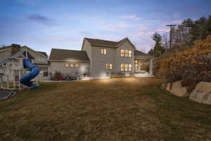 Rear view of property featuring a patio, stucco siding, a shingled roof, and a playground
