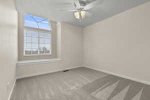 Spare room with light carpet and a ceiling fan