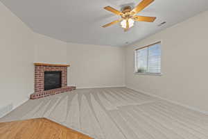Unfurnished living room featuring a fireplace, a ceiling fan, and light carpet