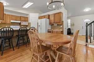 Dining room featuring lofted ceiling, light wood-style flooring, and a chandelier
