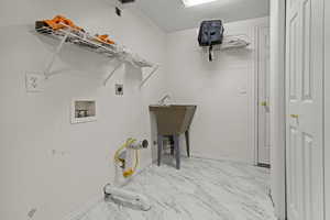 Laundry area featuring hookup for a washing machine, light marble finish floors, and hookup for an electric dryer