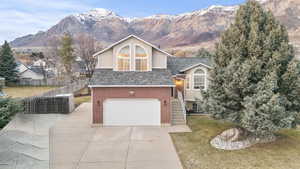 View of front of home with a garage, driveway, a mountain view, stucco siding, and stone siding
