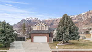 View of front of home with a garage, a mountain view, driveway, stone siding, and brick siding