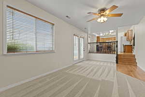 Unfurnished living room featuring ceiling fan and light carpet