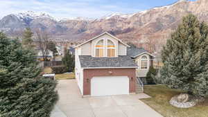 View of front facade featuring driveway, a mountain view, a garage, stone siding, and stucco siding
