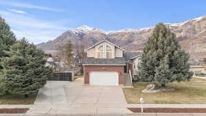 View of front facade with a garage, concrete driveway, a mountain view, and brick siding