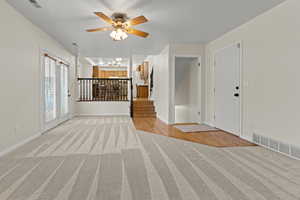 Entrance foyer featuring light colored carpet and a ceiling fan