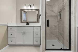 Full bathroom featuring vanity, a marble finish shower, and light tile patterned floors