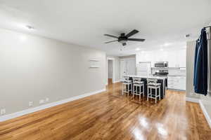 Kitchen with light countertops, white cabinetry, stainless steel appliances, light wood-style flooring, and a ceiling fan