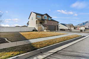 Traditional home featuring a gate, brick siding, driveway, an attached garage, and a mountain view