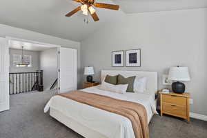 Primary bedroom featuring carpet floors, lofted ceiling and a ceiling fan