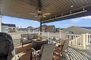 Wooden terrace with a residential view, a ceiling fan, a grill, and an outdoor lounge area