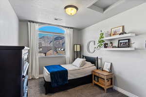Bedroom with dark carpet and a textured ceiling