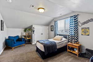 Bedroom with a textured ceiling and dark colored carpet