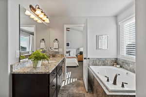 Ensuite bathroom featuring vanity and a bath