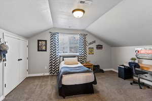 Carpeted bedroom featuring a textured ceiling and baseboards