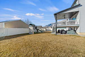 Fenced backyard with a playground, covered deck with ceiling fan and mountain views