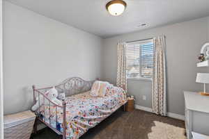 Bedroom featuring dark carpet and baseboards