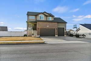 View of front of property with brick siding, concrete driveway, stucco siding, a porch, and a garage