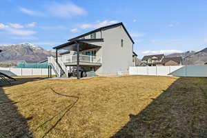 Rear view of house with a fenced backyard, and a covered deck with mountain view