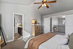 Bedroom with dark colored carpet, a ceiling fan, and ensuite bathroom