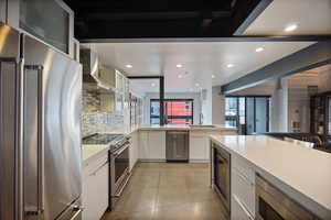 Kitchen with stainless steel appliances, glass fronted cabinets, recessed lighting, white cabinets, and beverage cooler