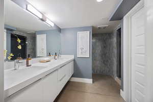 Full bathroom featuring a stall shower, double vanity, and concrete floors