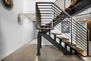 Stairway with finished concrete floors and recessed lighting heading to second level