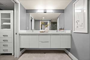Full bathroom with double vanity and a shower stall