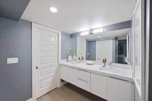 Full bath with double vanity, concrete floors, recessed lighting, and a stall shower