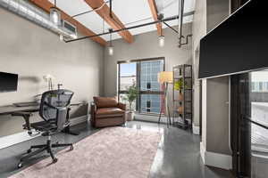 Home office featuring concrete flooring and baseboards