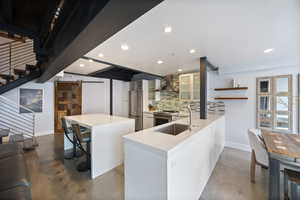 Kitchen featuring a barn door, glass fronted cabinets, finished concrete floors, a kitchen island, and stainless steel appliances