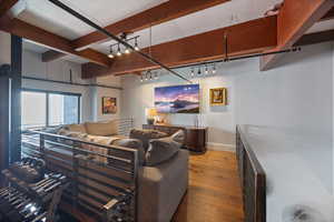 Living room featuring wood-type flooring, beam ceiling, and track lighting