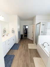 Ensuite bathroom with vanity, light wood-style flooring, a garden tub, and a shower stall
