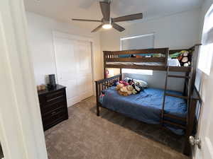 Bedroom featuring dark carpet, a closet, and a ceiling fan
