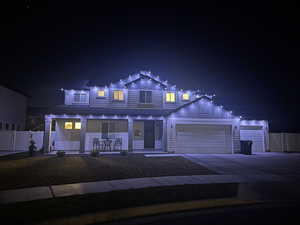 Traditional-style home featuring covered porch, driveway, a garage, board and batten siding, and a gate