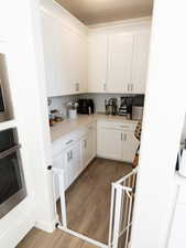 Kitchen featuring stainless steel appliances, dark wood-type flooring, white cabinetry, and decorative backsplash