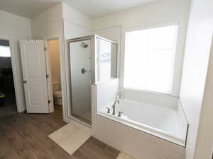 Bathroom with a stall shower, a bath, healthy amount of natural light, and dark wood-style floors