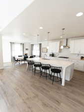 Kitchen featuring white cabinets, a kitchen breakfast bar, a spacious island, and light wood-style flooring